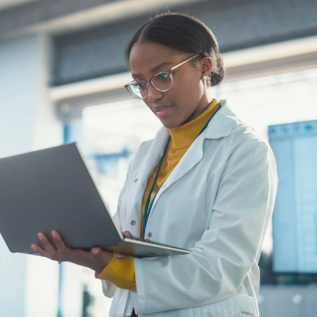 Specialist in Lab Coat Using Laptop