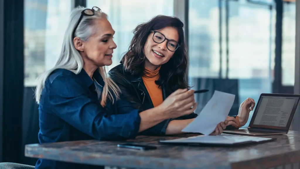 Two women analyzing documents at office